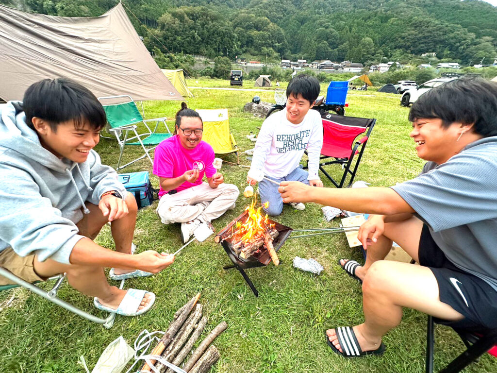 キャンプファイヤーでマシュマロを食べるフープファームメンバー